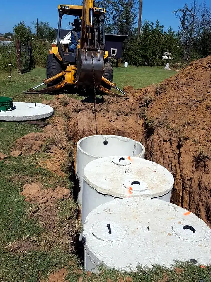 Backhoe setting tank risers on a new septic install