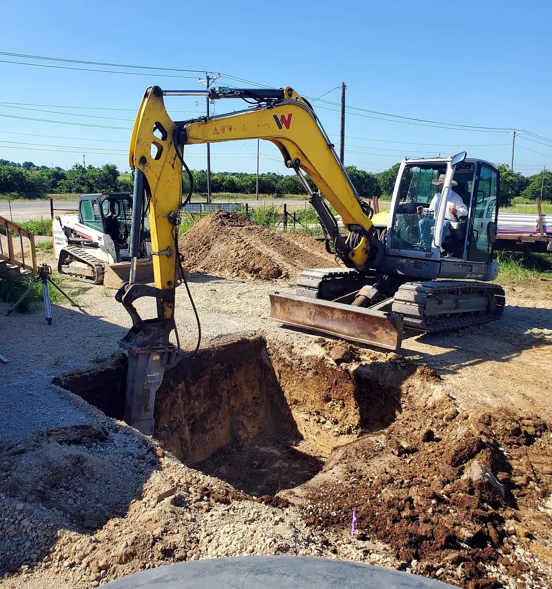 Excavator setting a new concrete septic tank