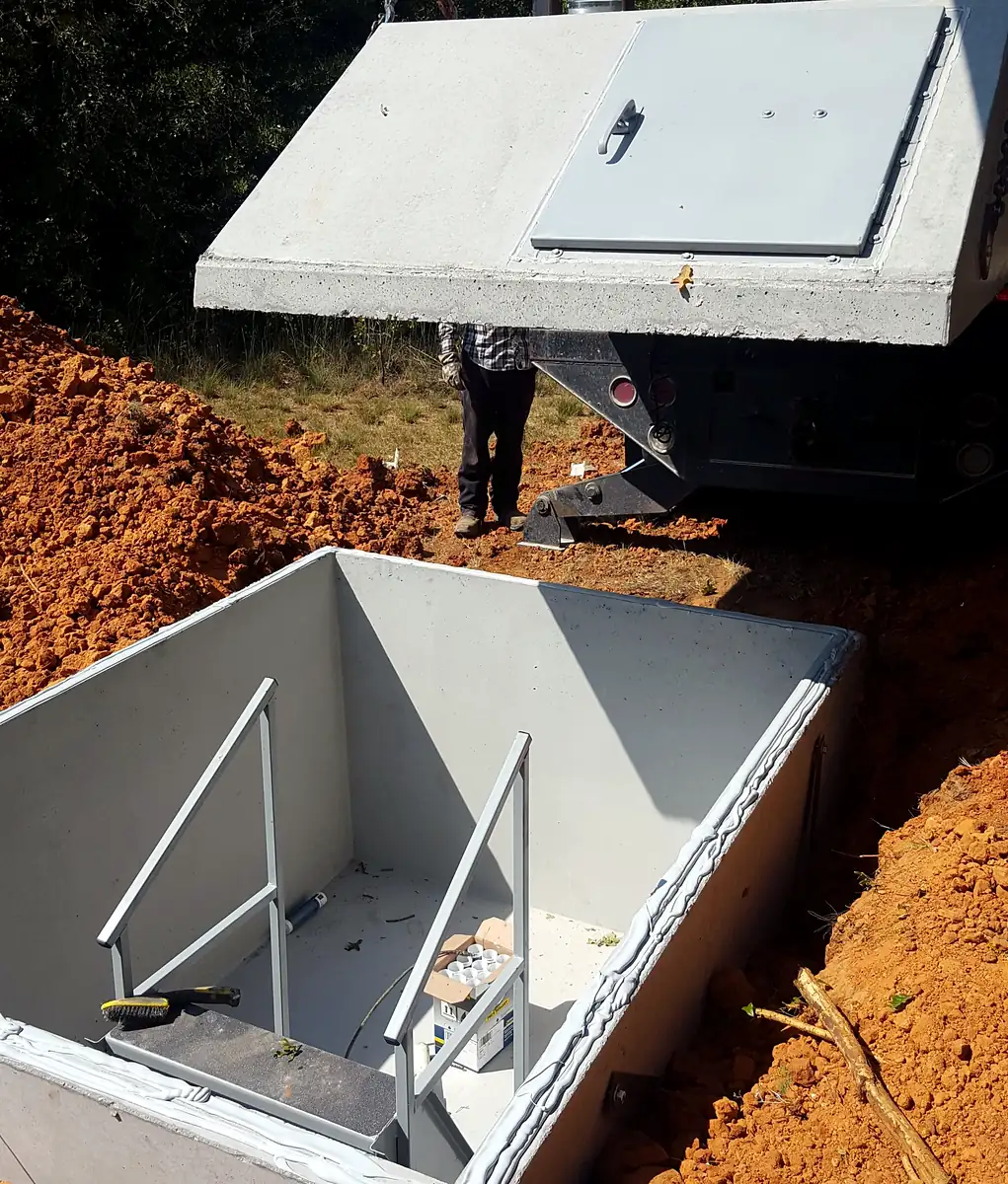 Crane lowering a Hausner storm shelter into the ground